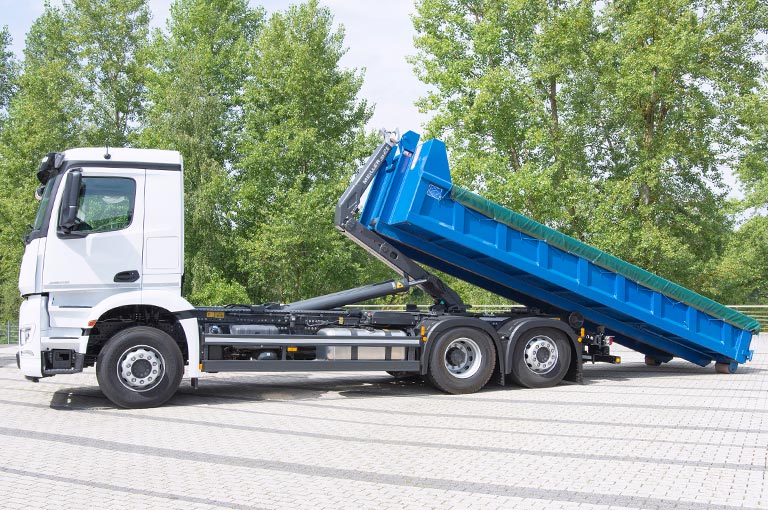 Hook loader truck with hydraulic hook-lift arm and roll-on container